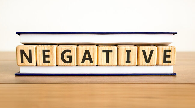 Negative word symbol. Concept word Negative on beautiful wooden blocks in beautiful book. Beautiful wooden table white background. Business support help negative word concept. Copy space.