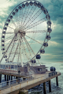 Riesenrad am Meer unter dramatischem Wolkenhimmel