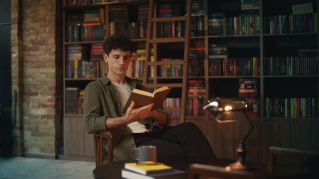 Relaxed young man reads historical literature while sitting in a coffee shop