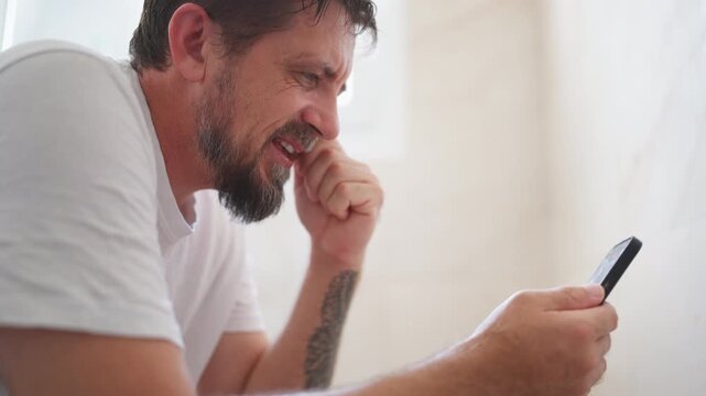 Middle-aged man sitting on toilet and looking at smartphone with a suggestive and interested expression, illustrating online attraction, private digital habits and modern technology use