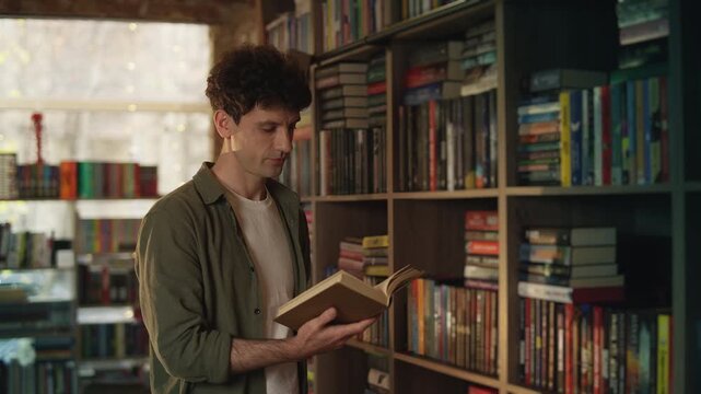 Young man reads new book and smiles in library, enjoying his favorite hobby