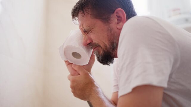 Adult man experiencing discomfort while sitting on toilet, highlighting men's health, digestive problems, bowel difficulties and common health concerns in everyday life.