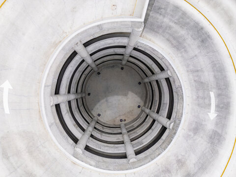 Aerial view of a concrete spiral ramp structure in a parking garage with directional arrows in Chihuahua, Chihuahua, Mexico.