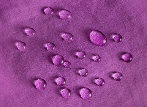 Purple lasting waterproof fabric with raindrops close up