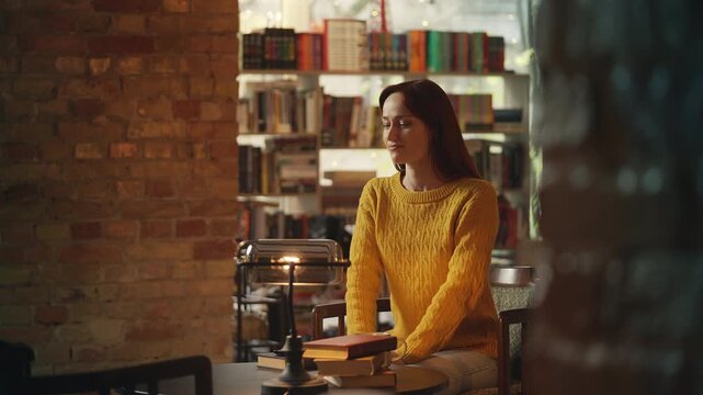 Young red-haired woman sits at table in coffee shop, waiting for her date