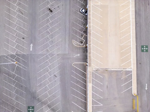 Aerial view of a parking lot with white painted lines, directional arrows, and a single parked car in Chihuahua, Chihuahua, Mexico.