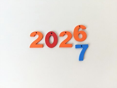 Colorful numbers arranged on white background, highlighting 2026 with additional 7 symbolizing transition or connection to 2027. Happy new year concept.