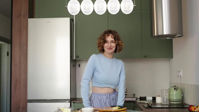 Woman bakes layered sponge cake in sunlit cozy kitchen, 25 fps