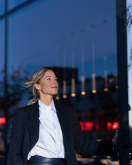 Fototapeta premium Businesswoman pushing open a glass door at a modern restaurant, wearing a tailored charcoal blazer for corporate lifestyle and business services