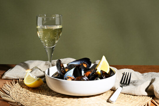 Cooked mussels in a bowl with a glass of wine