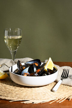 Cooked mussels in a bowl with a glass of wine