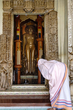 India. State of Madhya Pradesh. Khajuraho. A worshipper in white ceremonial robes prays before the monumental statue of a Tirthankara at the Shantinath Temple