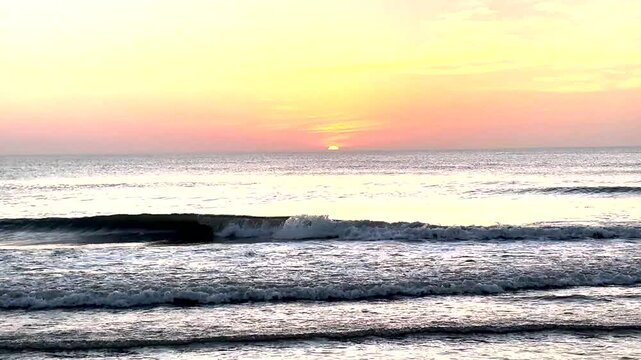 The sun rising over the ocean in Corolla North Carolina with Ocean waves crashing gently on the shore.