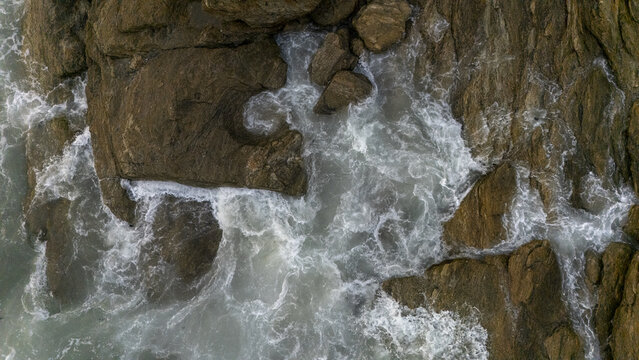 Aerial view of the rocky coastline at Sakumono Beach with white sea foam crashing against the rugged brown rocks Sakumono, Greater Accra Region, Ghana.