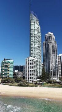 Surfers Paradise aerial view of waves rolling onto golden sand below the towers, Gold Coast, Queensland Australia - vertical video