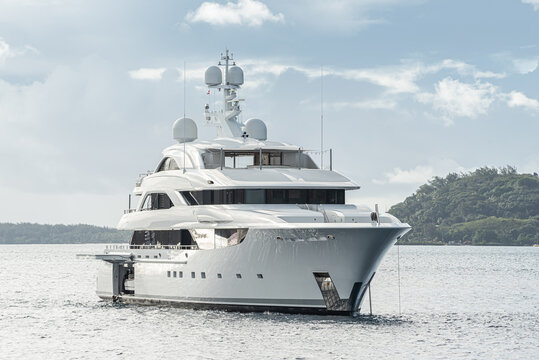 White superyacht at anchor in famous bay in Bora Bora, French Polynesia with green island in the background with blue sky with clouds
