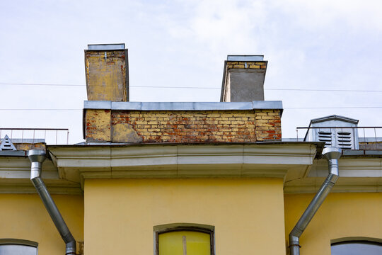 Weathered brick chimneys and metal flashing on old building roof