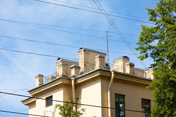 Old apartment building rooftop with brick chimneys and TV antenna © Mariia