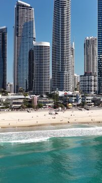 Surfers Paradise coastline from above, surf breaking beside the high-rise strip, Gold Coast, Queensland Australia - vertical video