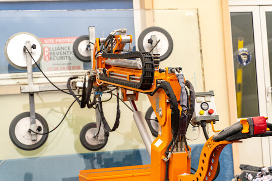 Orange glass handling robot beside a facade