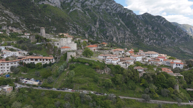 Aerial view of the historic Kruja Castle and town, featuring traditional stone buildings with terracotta rooftops nestled against the rugged mountainside in Kruje, Durres County, Albania.