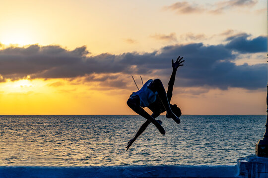 Acrobatic jump into the sea at sunset in Sao Luis, Maranhao.