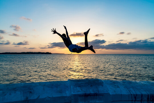 Boy jumping into the sea at sunset in Sao Luis, Maranhao.