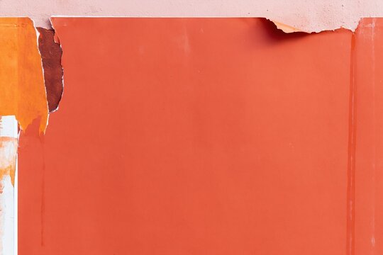 Torn wheatpaste poster with weathered orange paper on an urban wall, featuring ripped edges and water stains for a textured mockup background