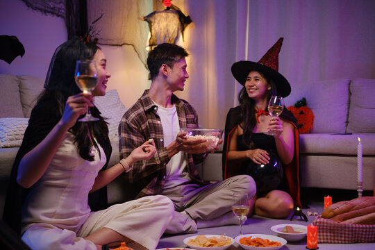 Young Asian friends sharing pizza together at a Halloween costume party.