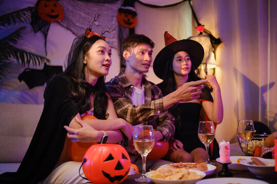 Young Asian friends celebrating together at a festive Halloween party at home.