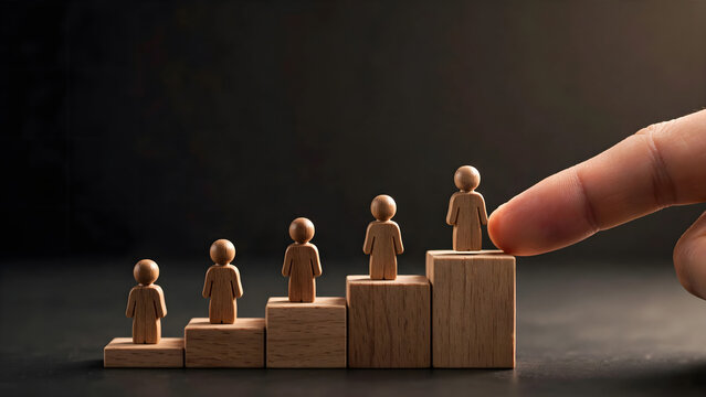 Wooden people figures standing on ascending blocks with hand selecting top position for career advancement concept