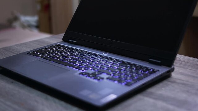 Male finger pressing power button on laptop computer, turning on device for work and technology use.