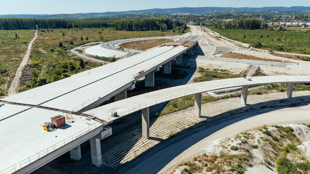 20 July 2026: Aerial view of a highway construction site with concrete overpasses, support pillars, and surrounding rural landscape under a clear sky.