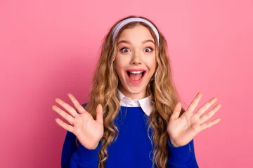 Fotobehang Sportwinkel Happy young girl in blue sweater with headband smiling against pink background  © deagreez
