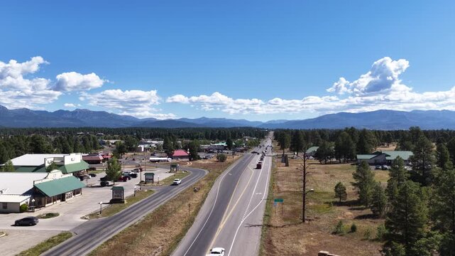 Aerial of US Highway 160 through Pagosa Springs Colorado in summer with commercial buildings and distant mountains under blue sky