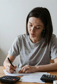 Personal finance management and budget planning, woman calculating expenses and taxes at home with calculators and documents