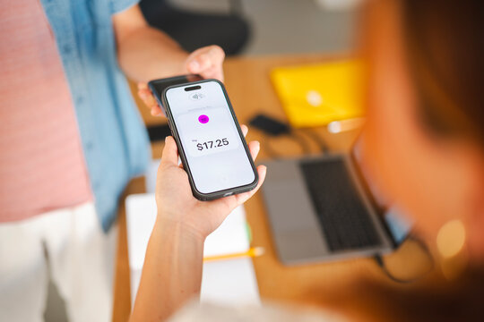 A customer uses their smartphone to make a secure contactless payment for a purchase at a checkout counter. The digital wallet screen displays the transaction amount.