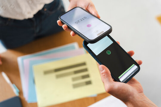 A customer pays for a transaction by tapping their smartphone against a merchant mobile device. This secure digital payment process occurs in a professional office.