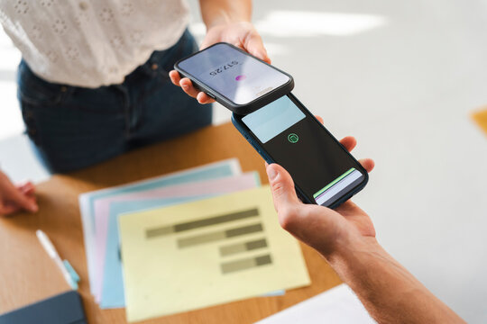 A person makes a contactless mobile payment by holding their smartphone against another device. This modern, efficient process illustrates digital financial trends.