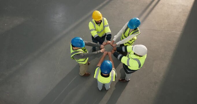 Group, circle and architect with fist bump in warehouse for construction solidarity in top view. People, contractor team and above of hands together for collaboration, motivation or unity in depot