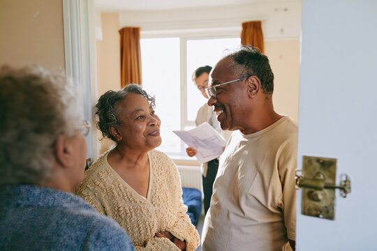 Senior Black couple standing in a bare room, sharing a natural, bittersweet moment during a home move for real estate and lifestyle content