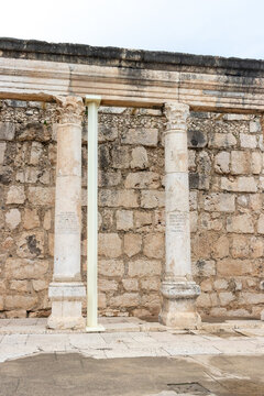 Capernaum, Israel - 08 March 2015: View of the ancient limestone columns and weathered stone wall of the historic synagogue.