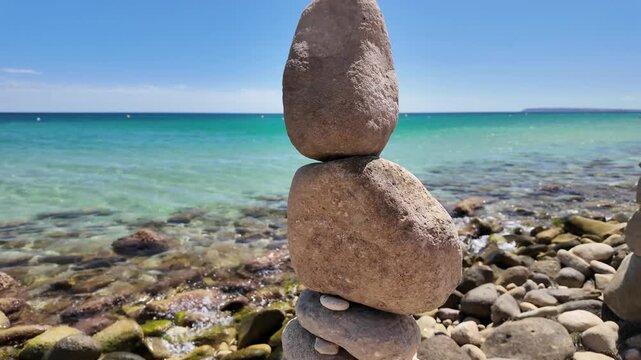 Zen stone cairns balance on smooth pebbles near a serene turquoise sea, capturing tranquility suited for relaxation apps and mindfulness campaigns