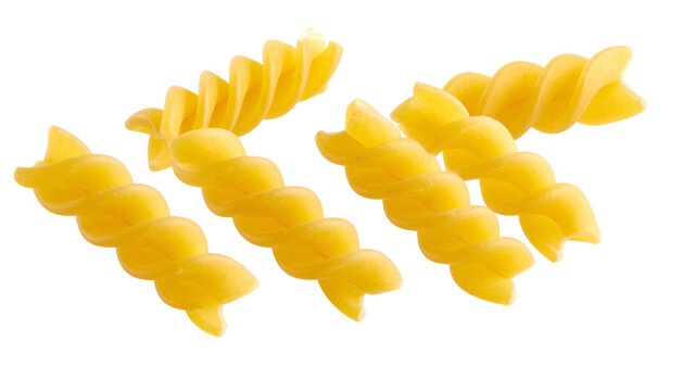 Close-up of golden, spiral-shaped pasta pieces, isolated against a solid black background. The pasta is uncooked