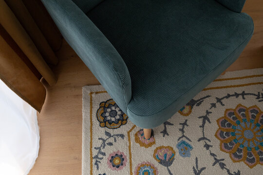 Close-up of a teal upholstered armchair and patterned rug in a modern interior