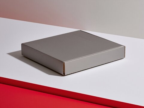 Blank rectangular cardboard box with a matte grey finish and a crushed corner, resting on a white surface for a shipping mockup and brand design copy space