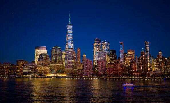 New York cityscape with storm clouds. New York golden light hits towers. New York City frames Manhattan waterfront. NYC skyline reflection on water.