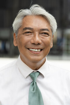 happy smiling southeast asian senior businessman portrait outdoors in the city during daytime, confident and professional