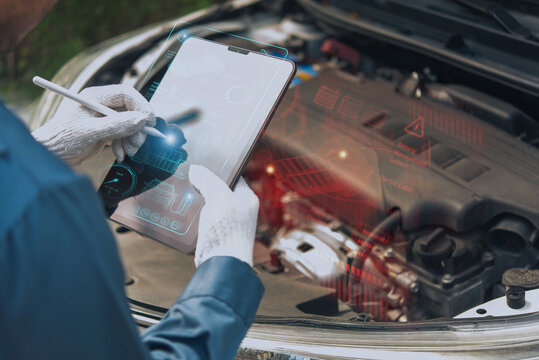 Auto technician examining car engine with smart tablet showing holographic data, photo manipulation, not AI.
