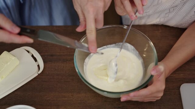 Mother and daughter whisking cream together in cozy kitchen hands focus